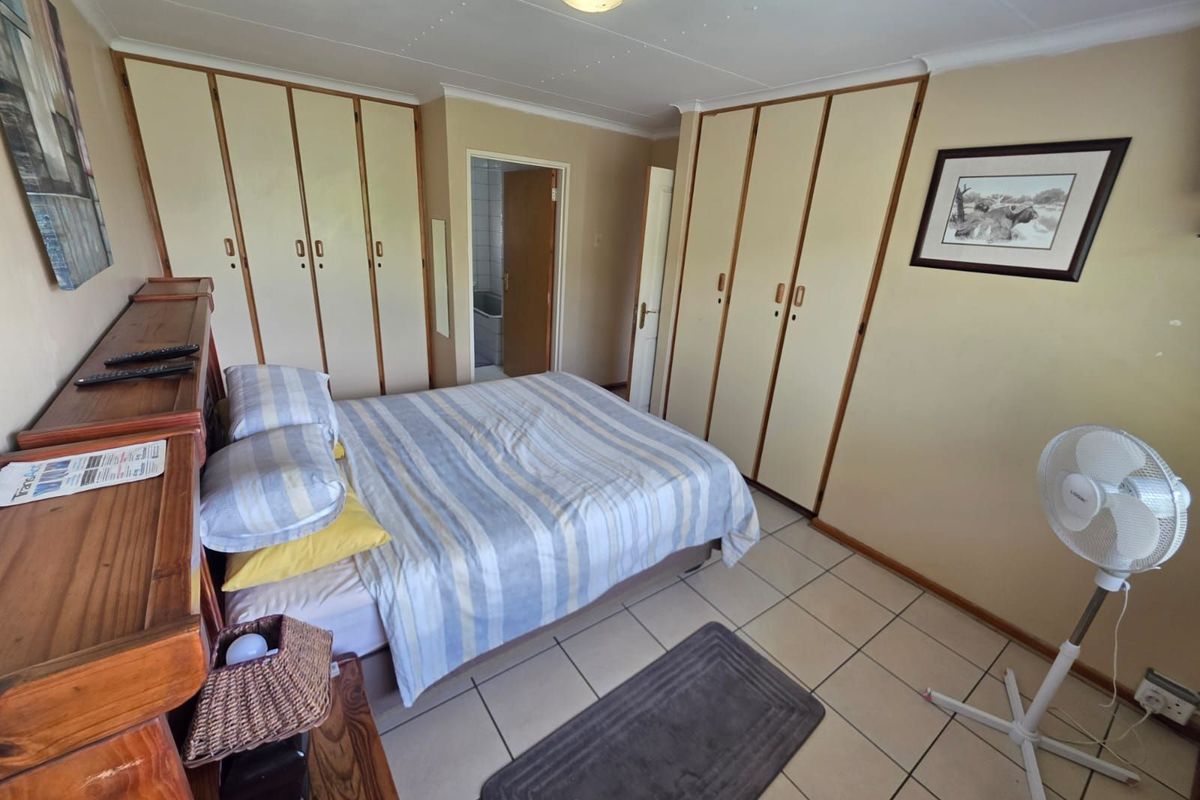 A functional bedroom featuring extensive built-in cabinetry, tiled flooring, and an en-suite bathroom access point.