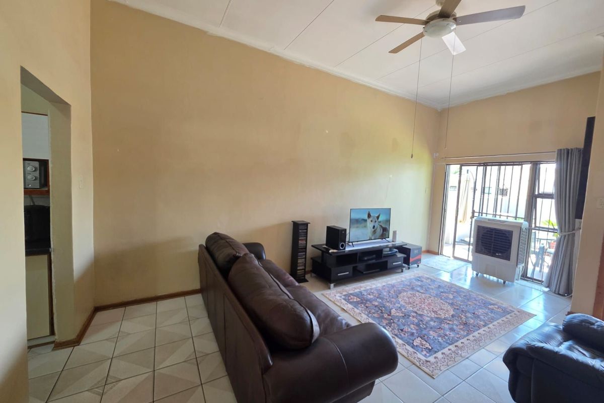 Spacious living room featuring tiled flooring, a ceiling fan, and sliding glass doors leading to an outdoor area.