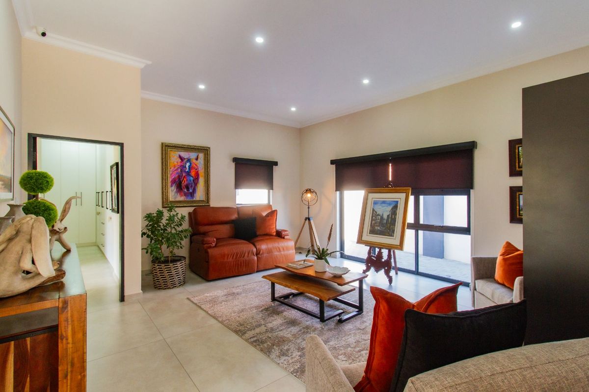 A well-lit living room featuring large sliding glass doors, recessed ceiling lighting, and neutral tiled flooring, providing a comfortable and inviting atmosphere.