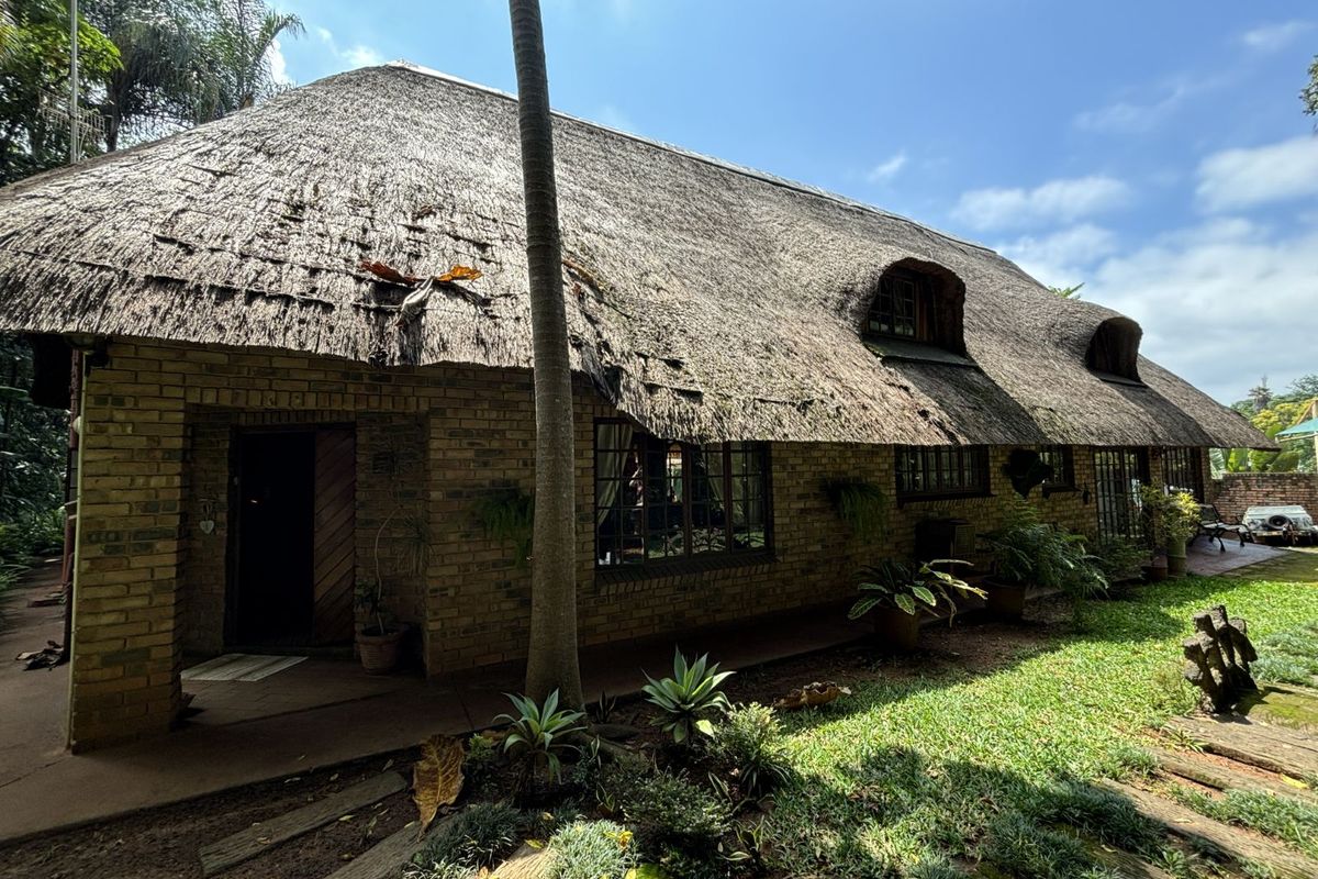 Exterior view of a rustic brick house featuring a traditional thatched roof with visible signs of wear and maintenance requirements.