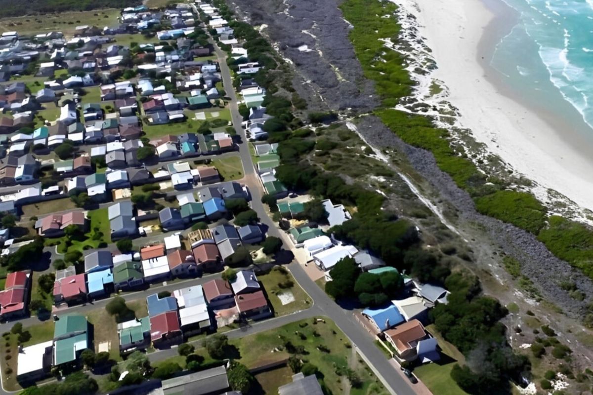 Aerial view of a coastal residential neighborhood situated directly adjacent to the beach and dunes.