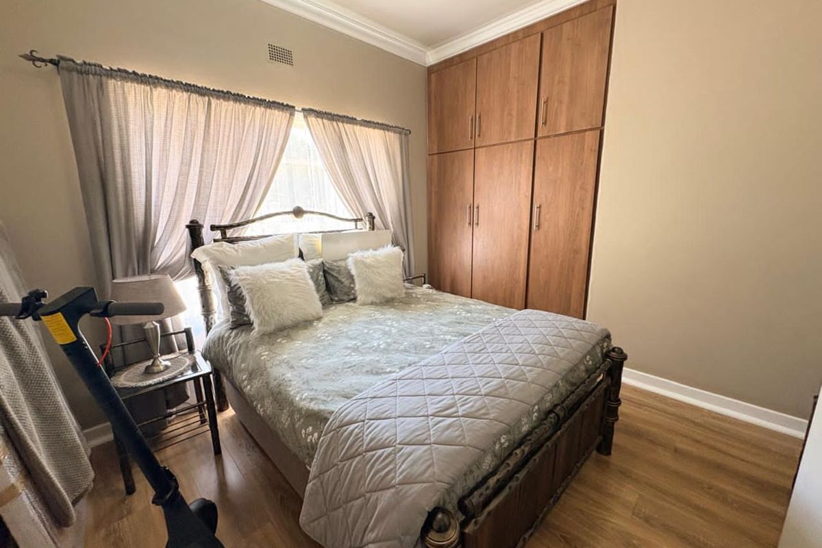 A well-maintained bedroom featuring built-in wooden cabinetry, laminate flooring, and crown molding.