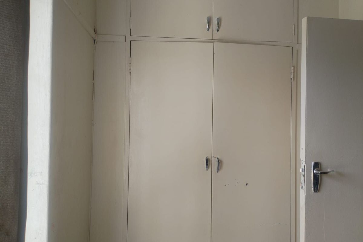 A bedroom featuring built-in floor-to-ceiling storage cupboards with overhead compartments, providing ample integrated closet space.