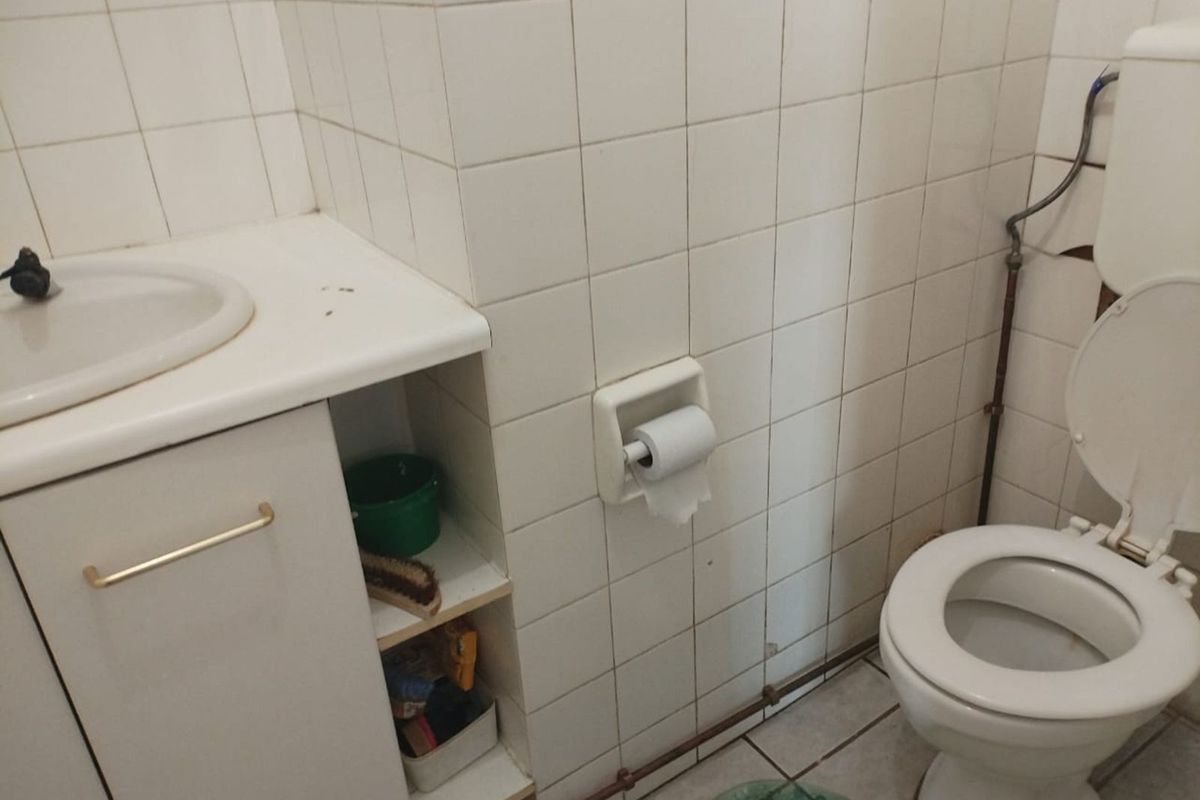 A compact bathroom featuring a built-in vanity with integrated basin, ceramic wall tiling, and a standard toilet suite.