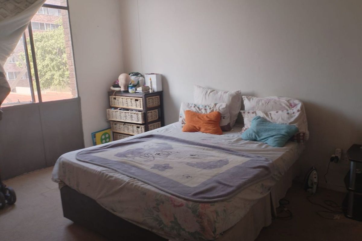 A bedroom featuring carpeted flooring and a large window providing natural light, offering a functional space for rest.