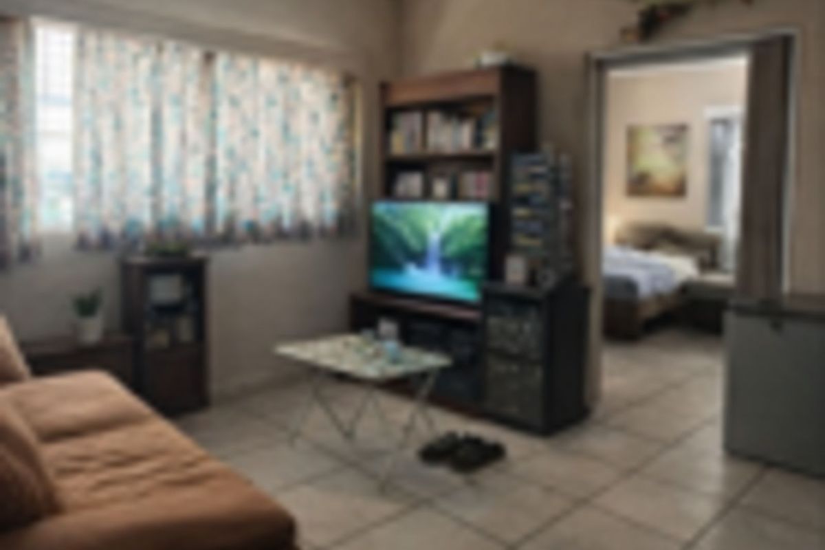 A living room area featuring tiled flooring and a doorway leading to an adjacent bedroom.
