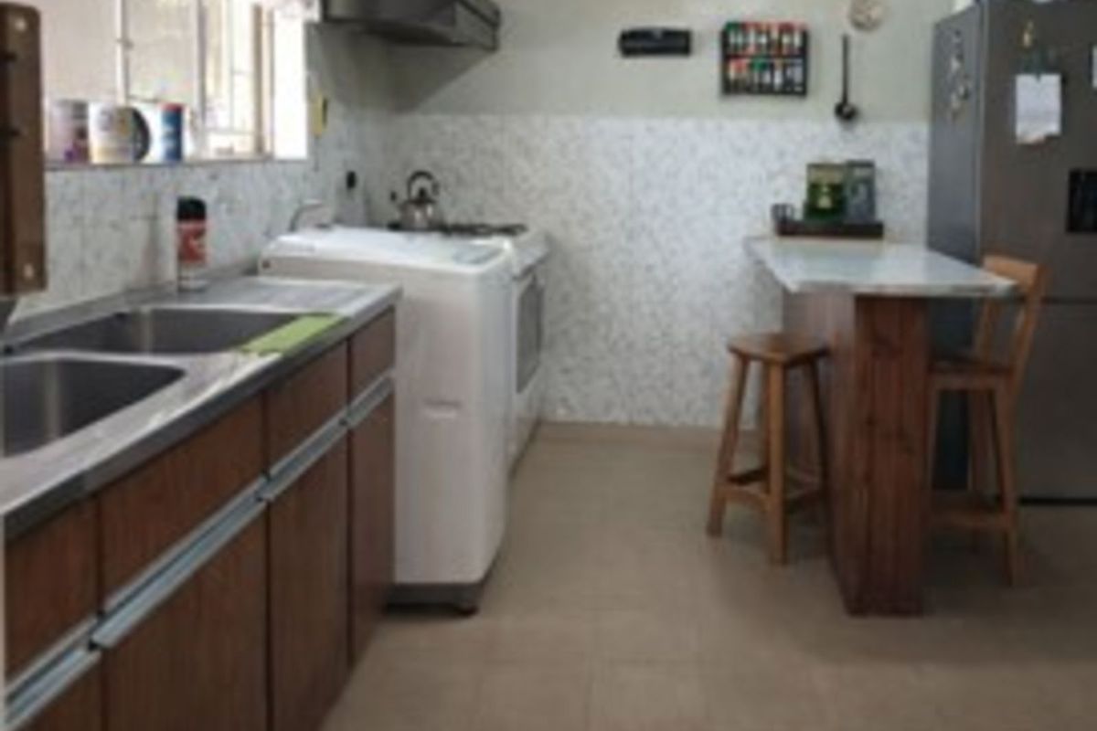 Functional kitchen featuring wooden cabinetry, stainless steel double sink, tiled splashback, and a built-in breakfast bar area.