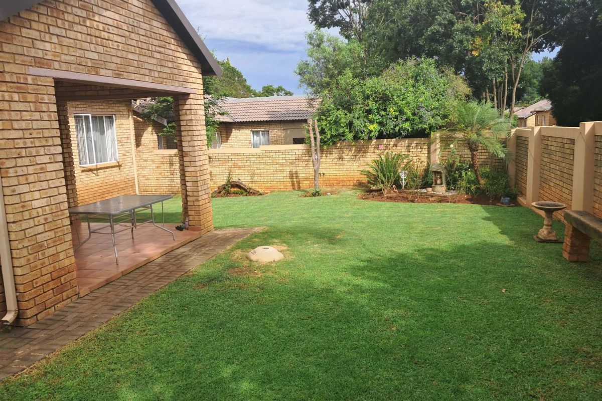 A private rear garden featuring a covered patio area, brick boundary walls, and a well-maintained lawn.