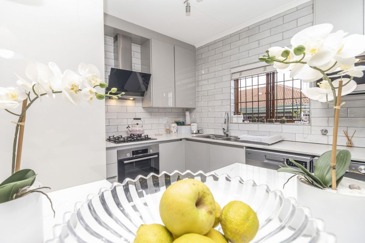 Modern kitchen featuring sleek grey cabinetry, subway tile backsplash, stainless steel oven, gas hob, extractor fan, and double basin sink with window view.