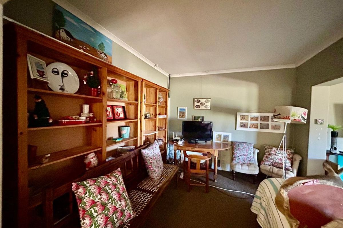 A cozy living room featuring built-in wooden shelving units and neutral wall finishes, providing a functional space for storage and relaxation.