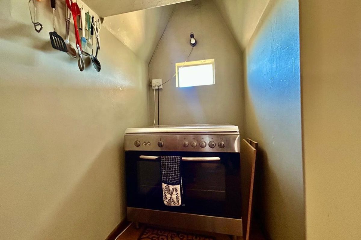A compact kitchen alcove featuring a freestanding stainless steel oven and stove unit, set within a small, enclosed space.
