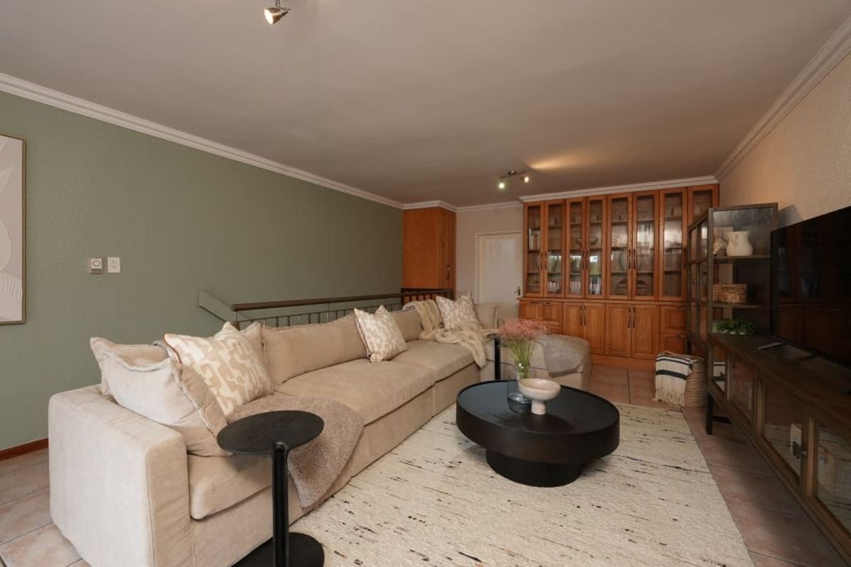A comfortable living room featuring built-in wooden cabinetry, tiled flooring, and a feature wall, providing a functional and inviting space.