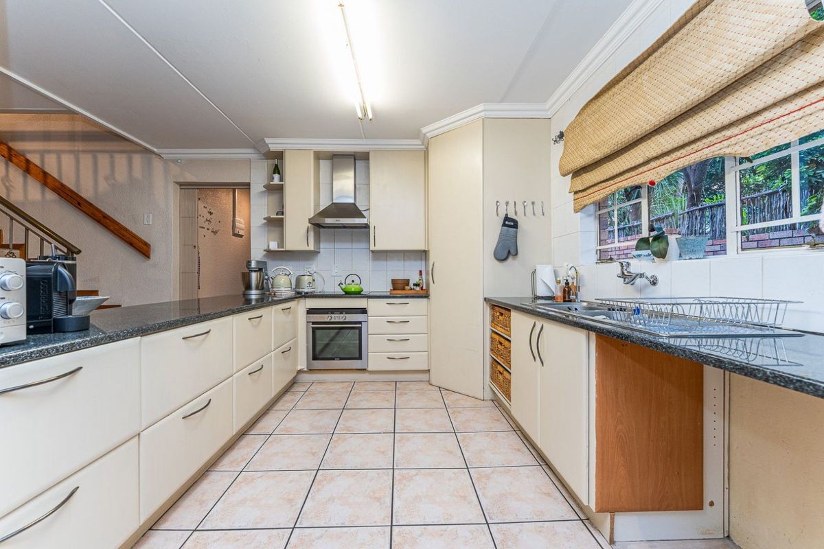 Functional kitchen featuring granite countertops, built-in oven, extractor fan, and tiled flooring, with a practical layout and ample storage cabinetry.