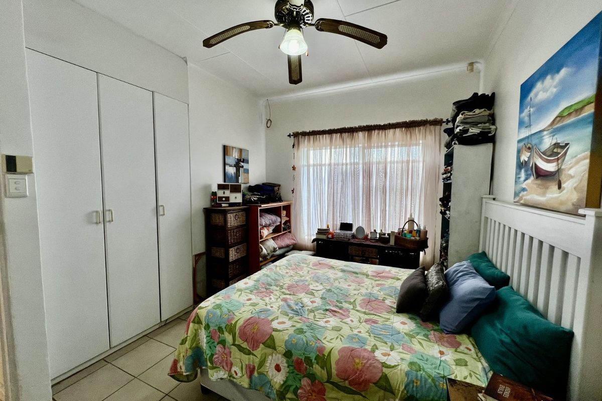 A bedroom featuring built-in wardrobes, tiled flooring, and a ceiling fan, providing a functional and comfortable living space.
