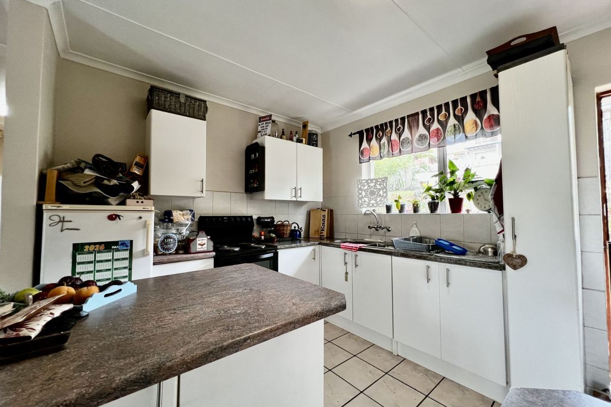 A functional kitchen featuring white cabinetry, laminate countertops, tiled backsplash, and a central island, providing a practical workspace for daily meal preparation.