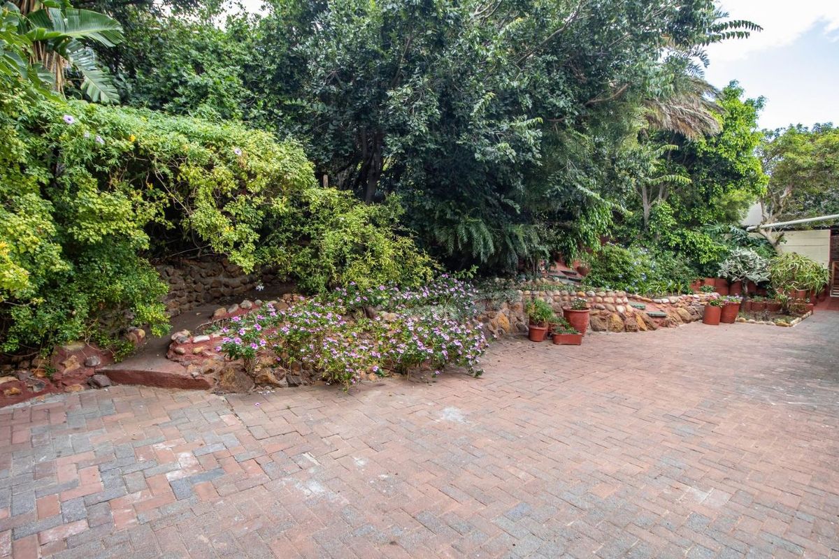 A paved rear courtyard area featuring a stone retaining wall and established garden landscaping, providing a private outdoor space.