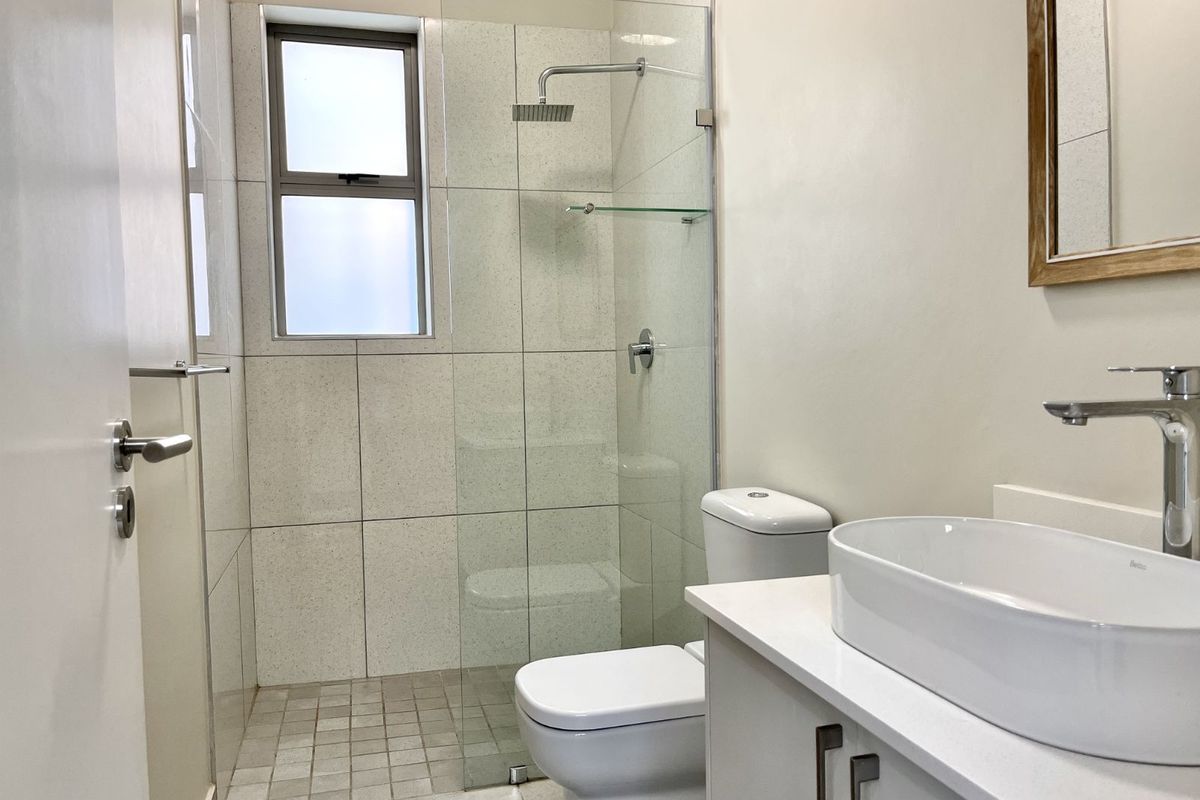 Modern bathroom featuring a glass-enclosed walk-in shower, contemporary vanity with a vessel sink, and neutral tiled finishes.