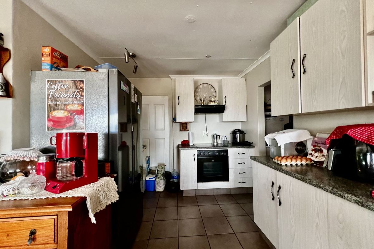 A functional kitchen featuring light-toned cabinetry, built-in oven, extractor fan, and tiled flooring, providing a practical layout for daily meal preparation.