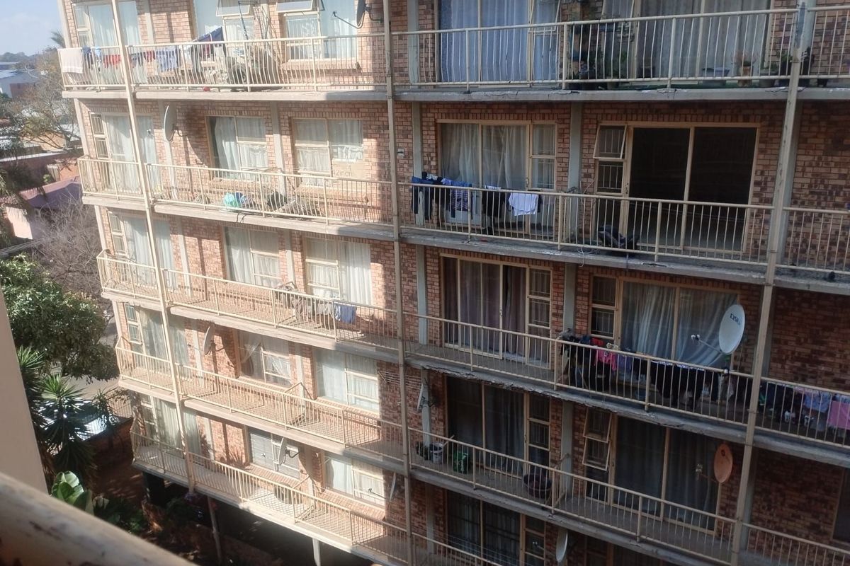 Exterior view of a multi-story apartment building featuring face-brick facade and private balconies with metal railings.