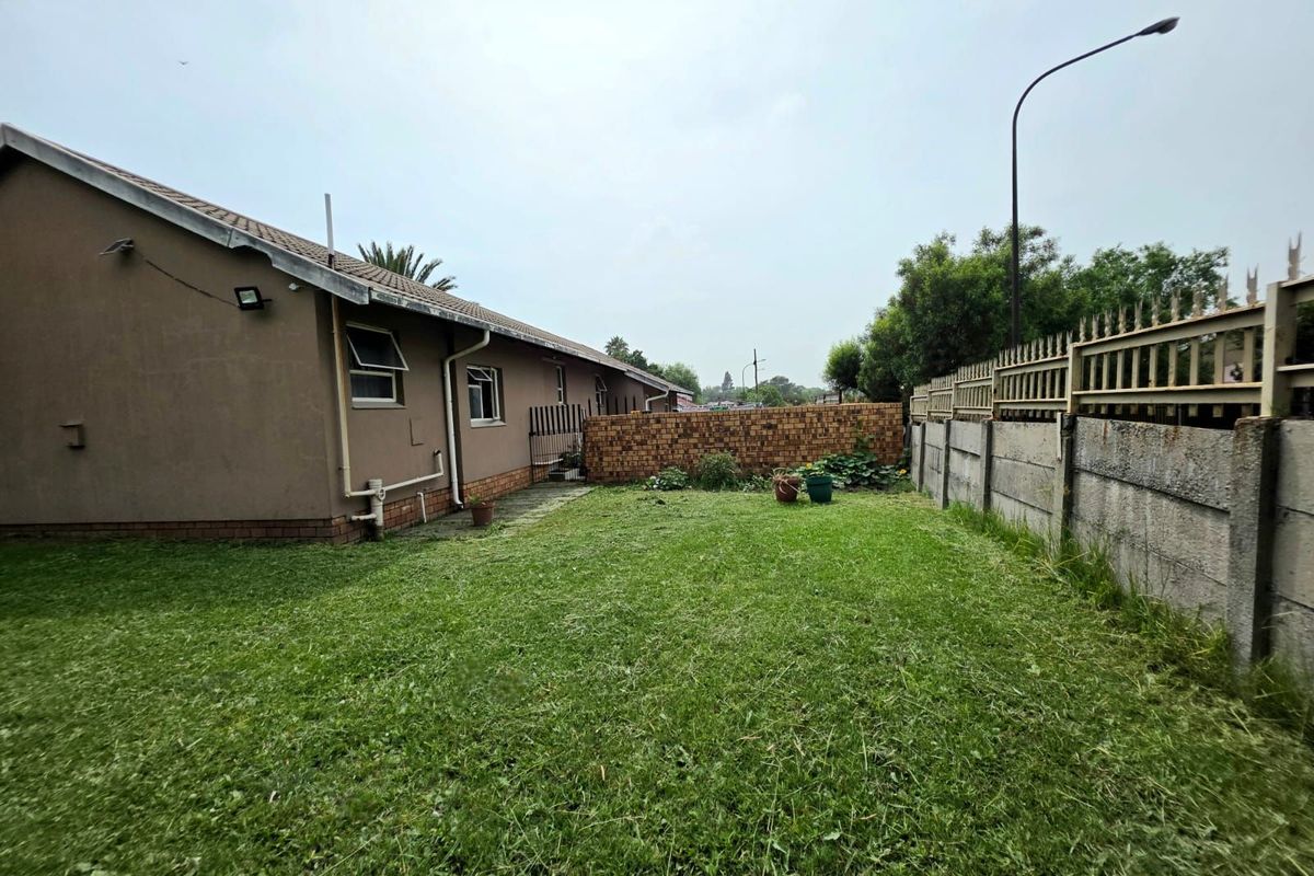 A view of the rear garden featuring a lawn area, perimeter boundary walls, and the side elevation of the house.