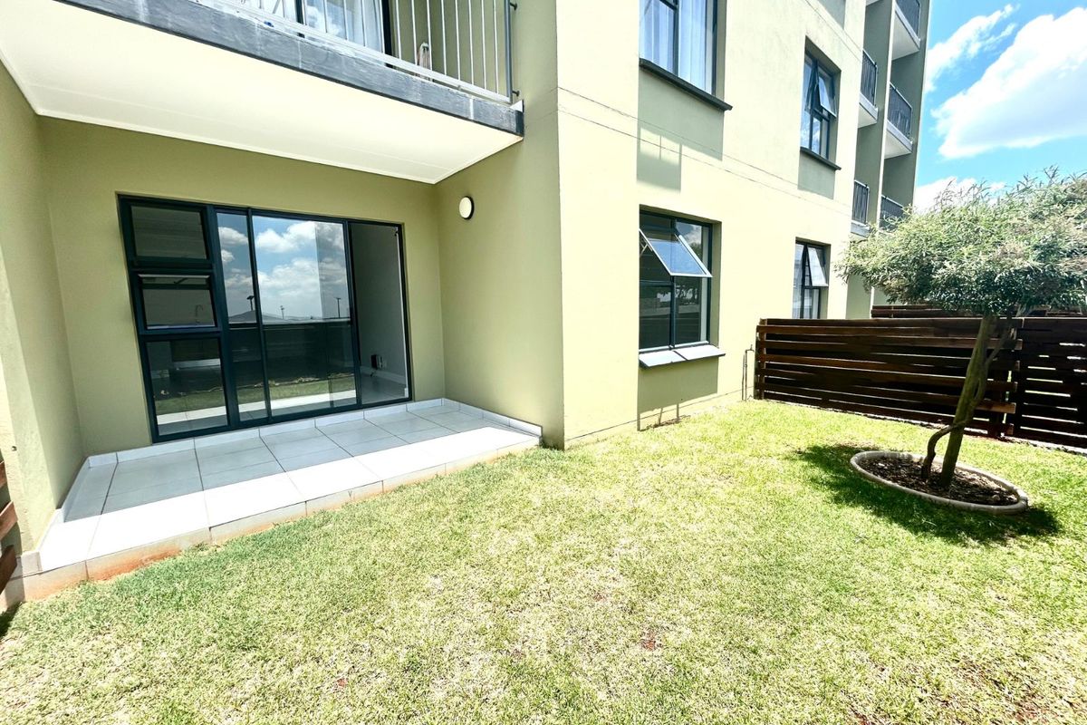 Ground floor apartment featuring a private tiled patio area, small garden space, and modern aluminum-framed windows and sliding doors.