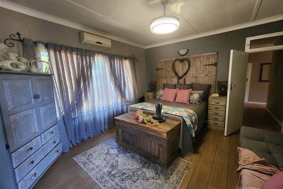 A well-maintained bedroom featuring wood-look tile flooring, a wall-mounted air conditioning unit, and a ceiling fan with integrated lighting.