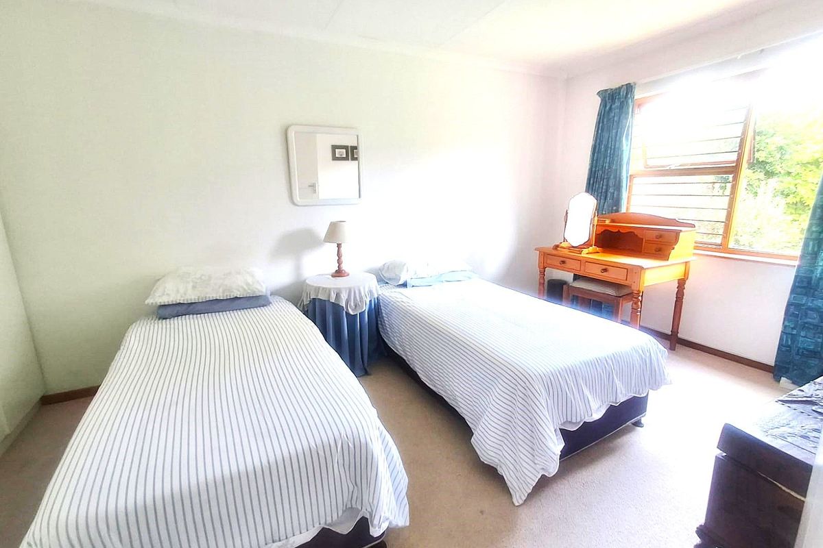 A bedroom featuring carpeted flooring and a large window with natural light, providing a functional space for rest.