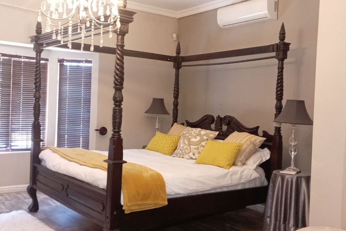 A well-maintained bedroom featuring a split-system air conditioning unit, crown molding, and wooden blinds.