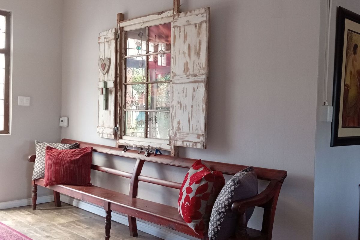 A bright living area featuring tiled flooring, neutral wall finishes, and a decorative wall-mounted window frame feature.