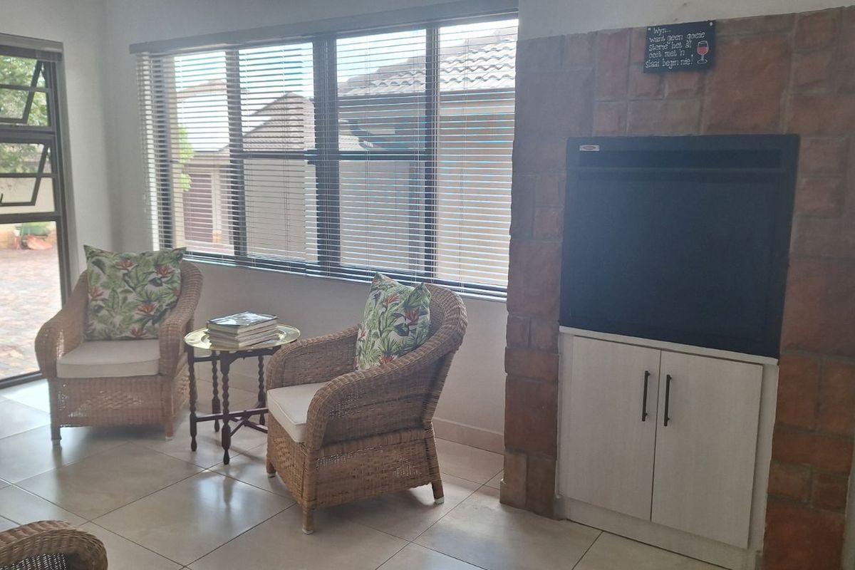 A living area featuring large windows with blinds, tiled flooring, and a built-in fireplace with a stone-clad surround and lower cabinetry.
