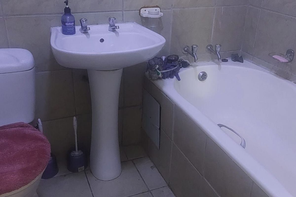A functional bathroom featuring a pedestal basin, toilet, and bathtub with tiled finishes throughout.