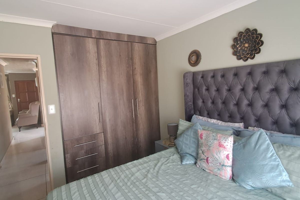 A well-maintained bedroom featuring built-in wooden cabinetry and a view into the adjacent hallway.