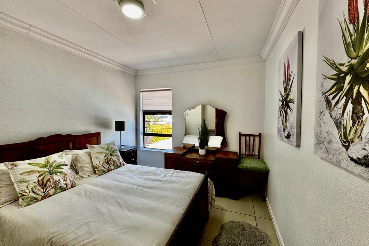 A functional bedroom featuring tiled flooring, crown molding, and a window providing natural light.