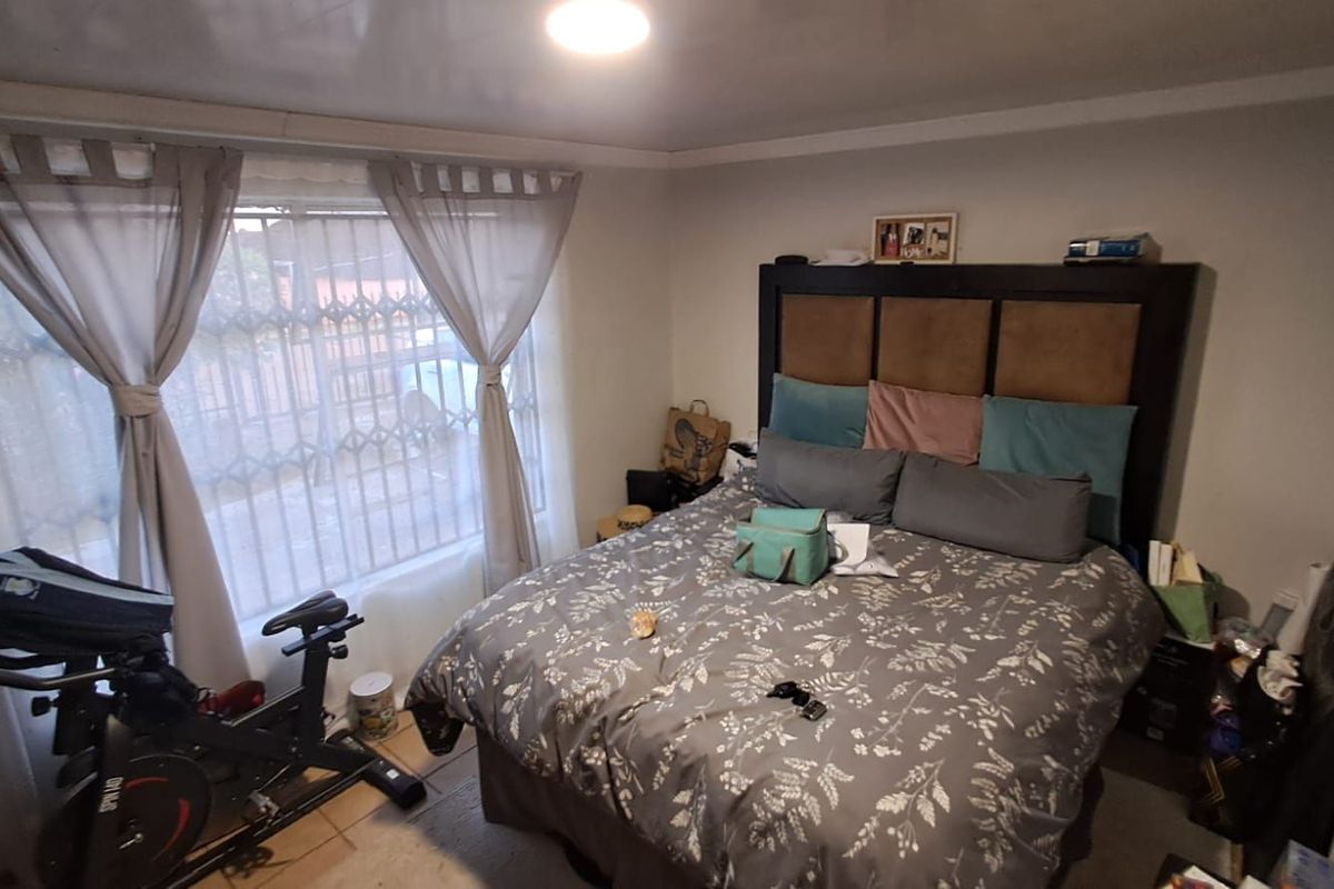 A bedroom featuring a window with security bars and tiled flooring.