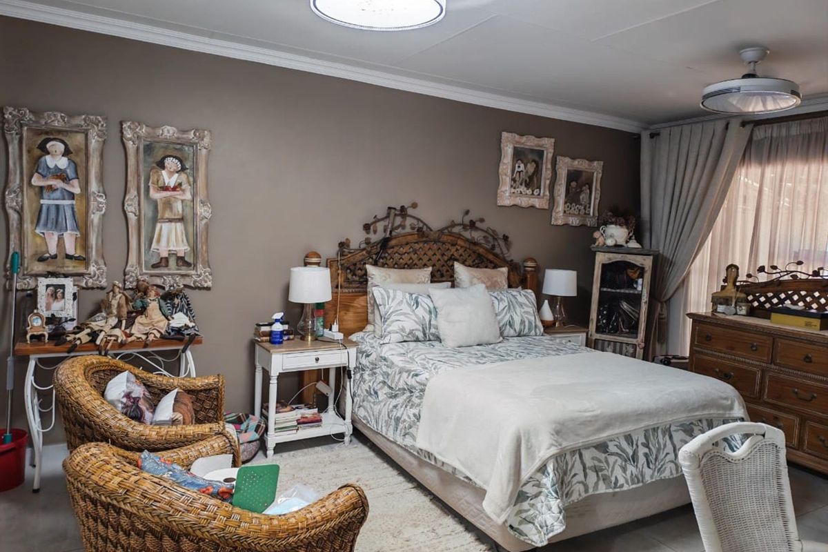 A well-maintained bedroom featuring neutral wall tones, crown molding, and dual ceiling-mounted light fixtures.