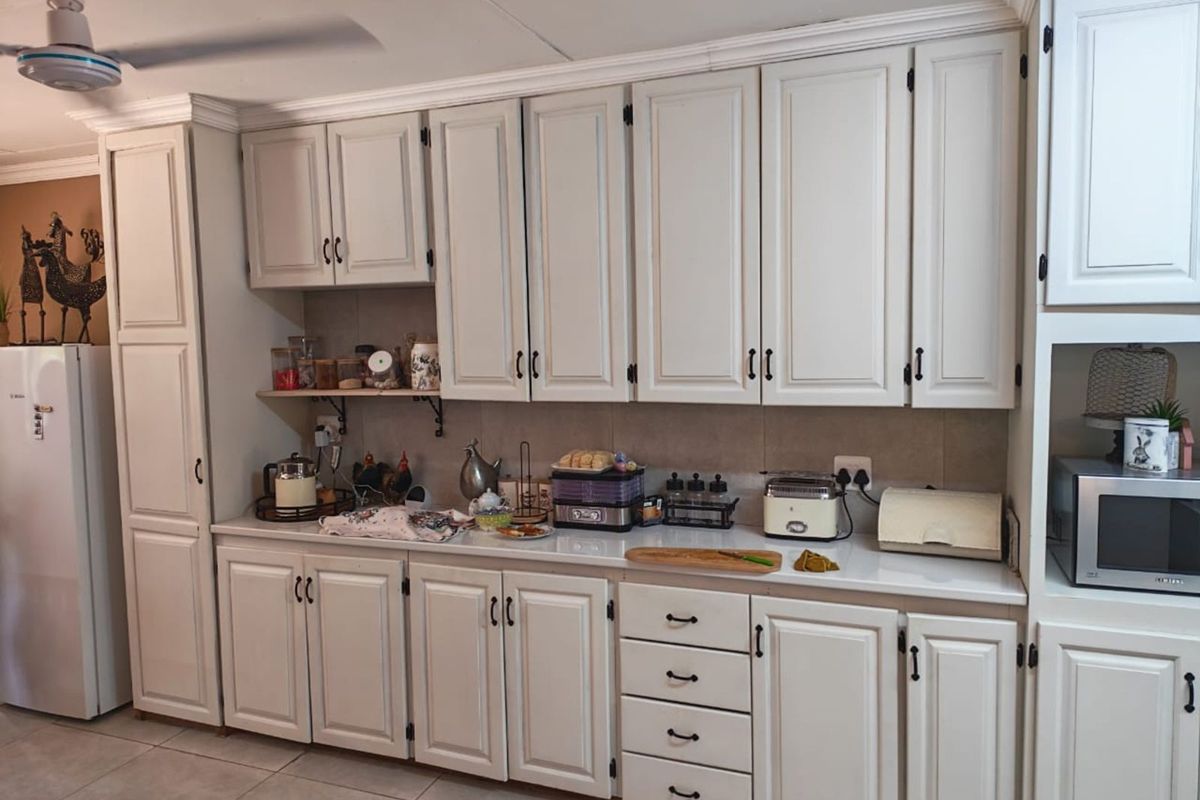 A functional kitchen featuring white cabinetry, tiled backsplash, and ample counter space, providing a clean and practical layout for daily meal preparation.
