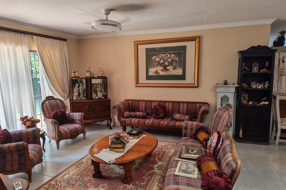 A comfortable living room featuring tiled flooring, a ceiling fan, and large sliding glass doors that provide natural light and garden access.