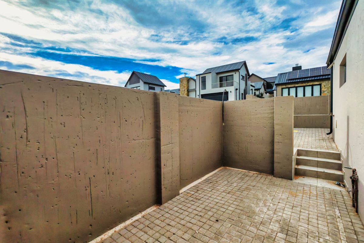 A private paved courtyard area featuring high concrete boundary walls and integrated steps, providing a secure and low-maintenance outdoor space.