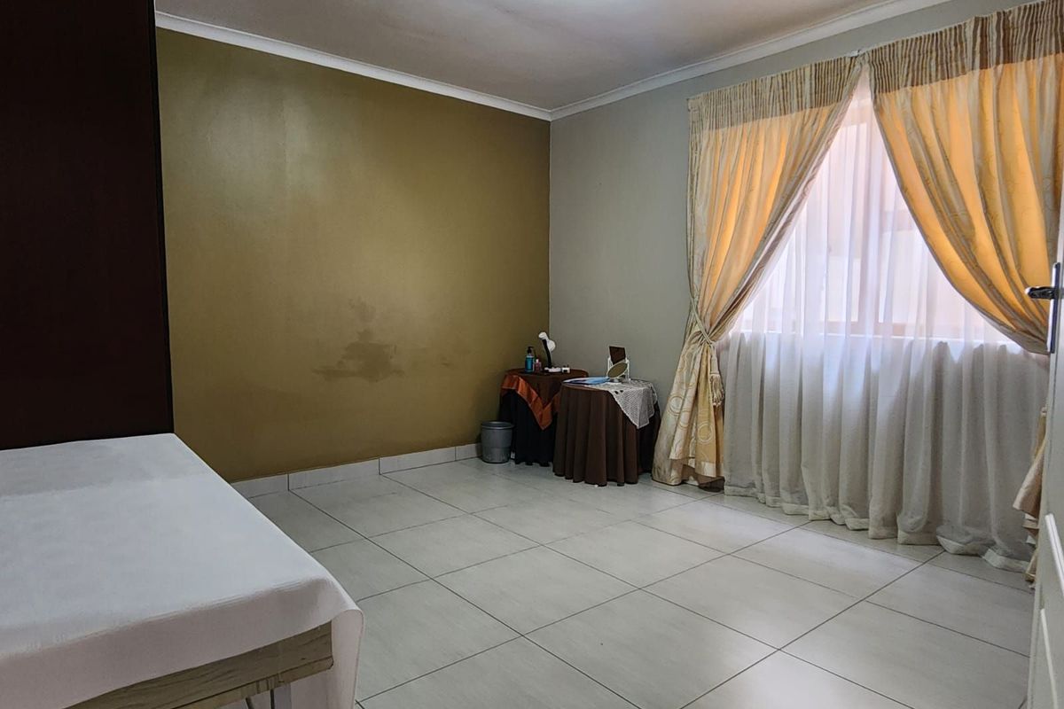A bedroom featuring tiled flooring, a large window with curtains, and a neutral color palette.