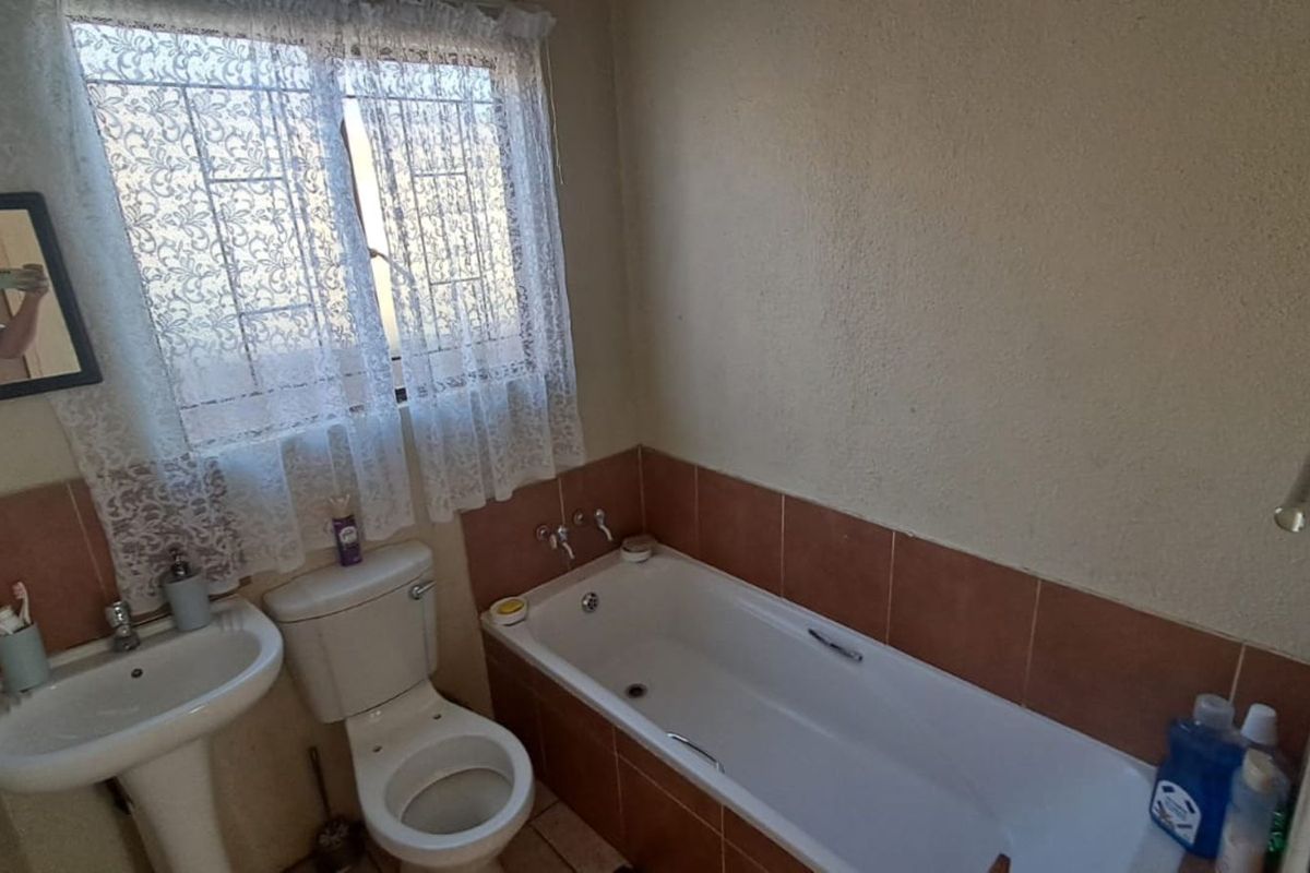 A functional bathroom featuring a pedestal basin, a standard toilet, and a built-in bathtub with tiled splashbacks.