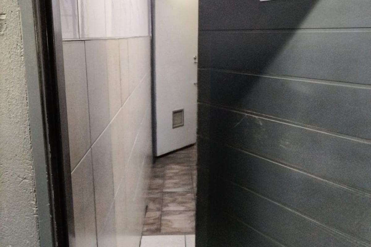 A view into a commercial restroom facility featuring tiled walls and flooring with a designated male signage on the door.