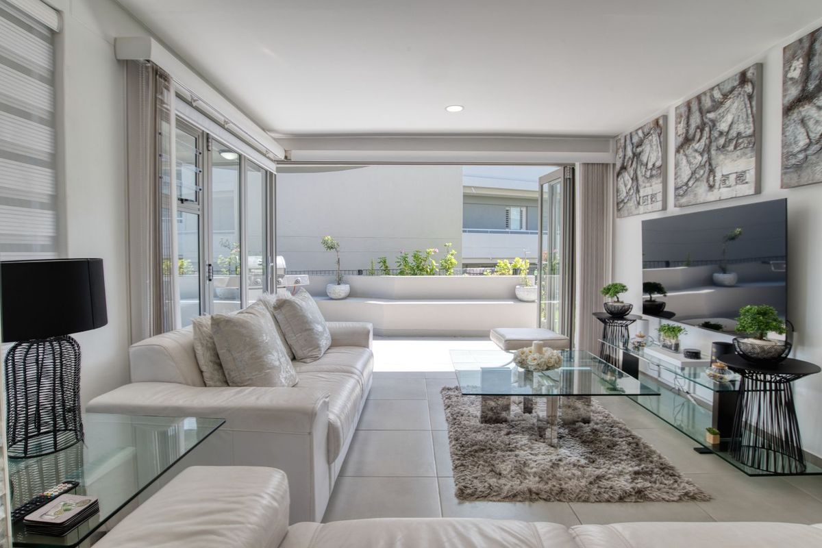 Modern living room featuring large glass sliding doors that open onto a private balcony, creating a seamless indoor-outdoor flow with abundant natural light.