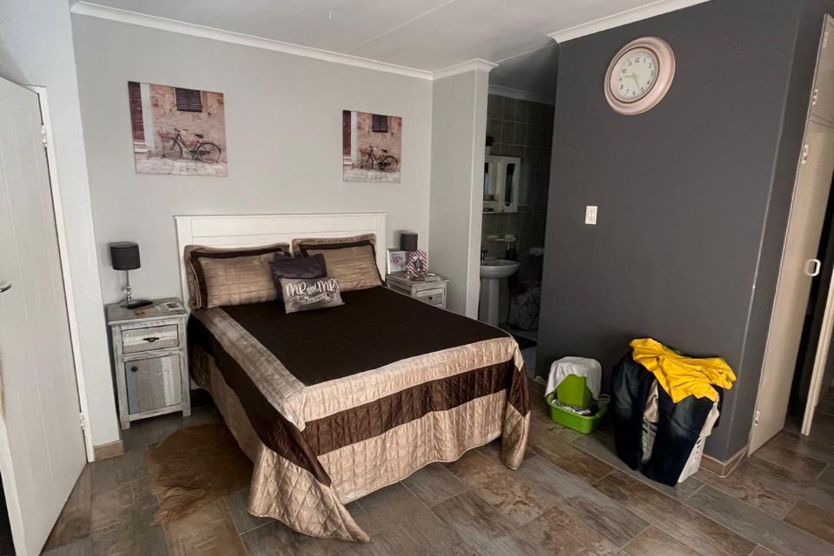 A bedroom featuring tiled flooring and an en-suite bathroom access point.