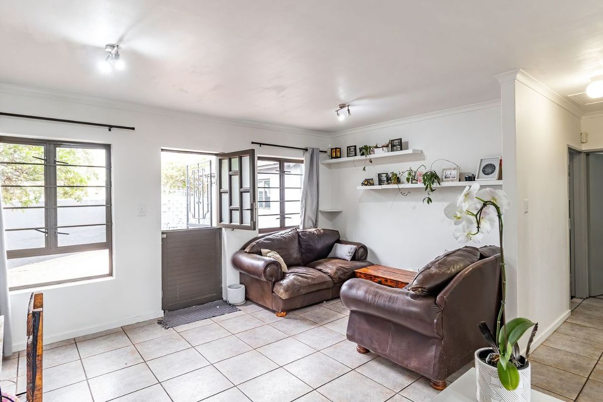 A bright living room featuring tiled flooring, large windows, and a stable-style door providing direct access to the exterior.