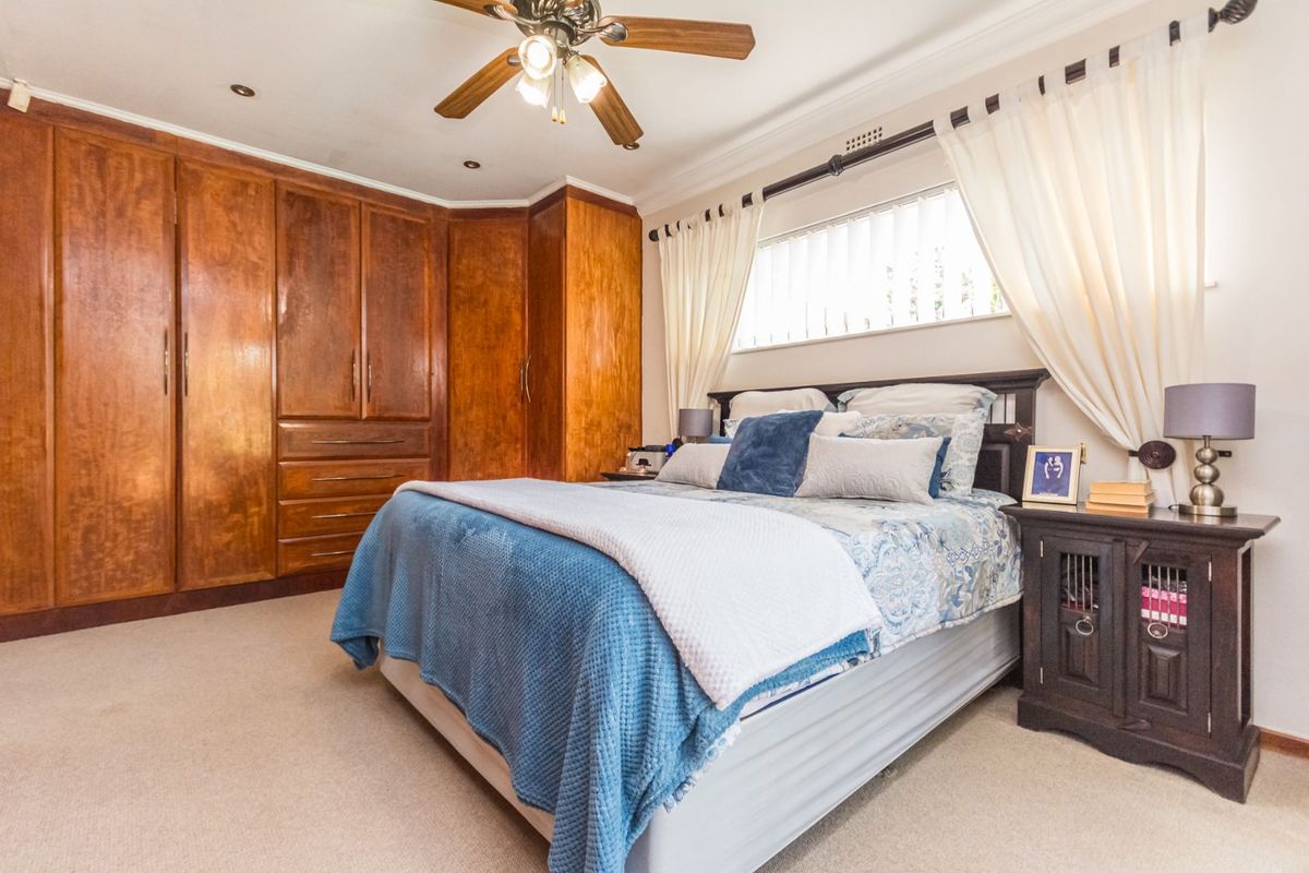 A bedroom featuring built-in wooden cabinetry, a ceiling fan, and carpeted flooring.