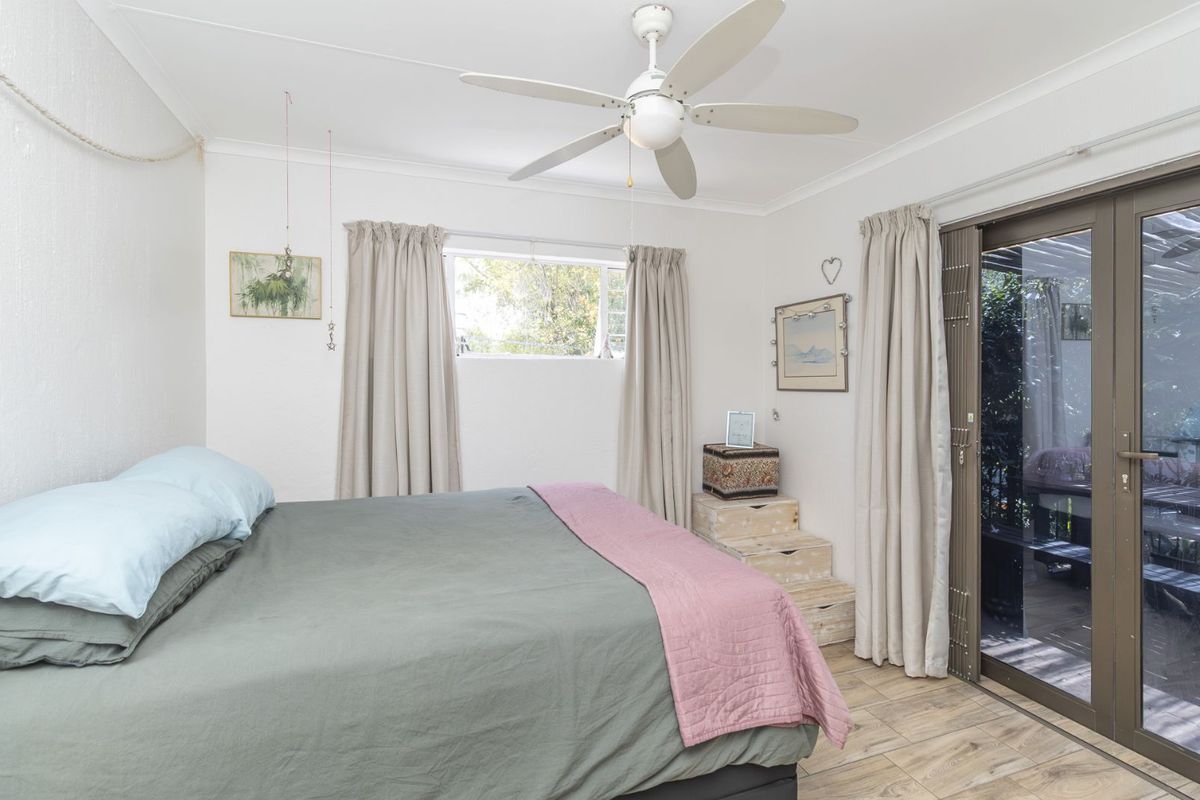 A bright bedroom featuring a ceiling fan, tiled flooring, and sliding glass doors providing direct access to an outdoor patio area.