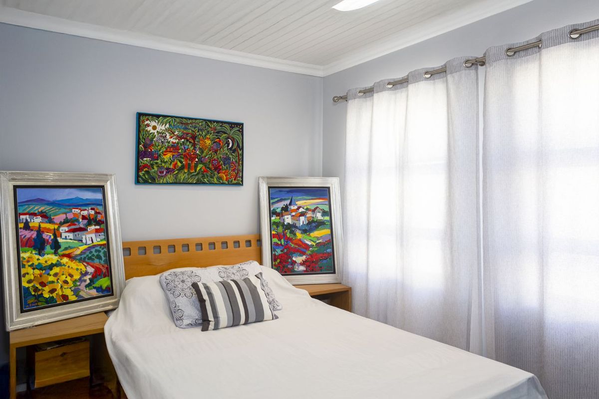 A bright and well-maintained bedroom featuring a tongue-and-groove ceiling, neutral wall finishes, and large windows with fitted curtain tracks.