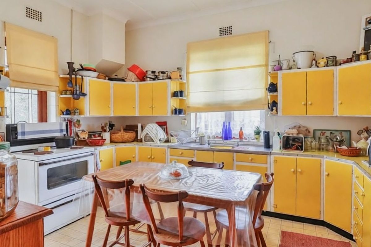 A dated kitchen featuring yellow cabinetry, a freestanding stove, and tiled flooring, offering significant potential for a modern renovation.
