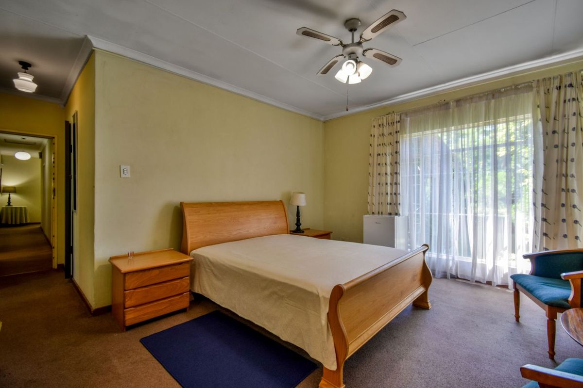 A spacious bedroom featuring a ceiling fan, carpeted flooring, and large sliding glass doors providing natural light and access to the exterior.