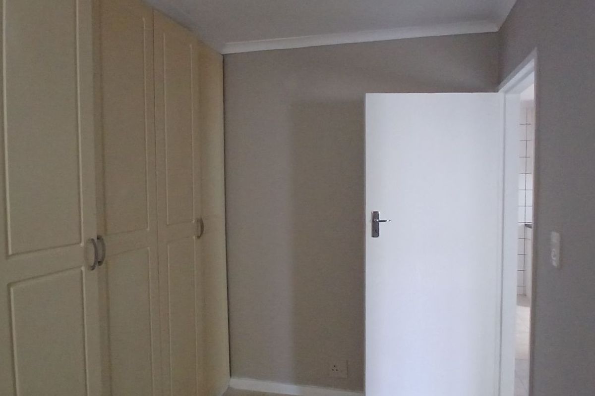 A bedroom featuring built-in cupboards and neutral wall finishes, providing a clean and functional space.